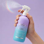 PixieYou 7-in-1 Benefits Detangler Leave-In Spray in a lavender bottle, being sprayed with a rainbow effect in the background