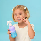 A young girl with blonde hair holds a PixieYou Detangler spray, smiling against a light blue background.