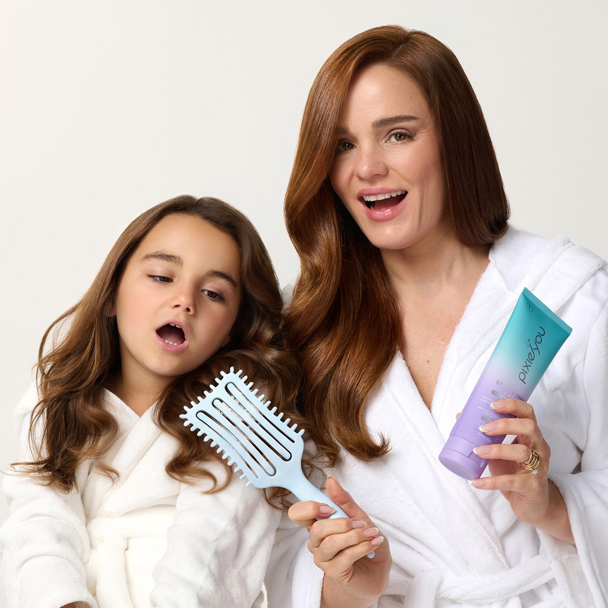 PixieYou Cloud Brush held by a woman and a girl, both in white robes, showcasing shiny, styled hair.