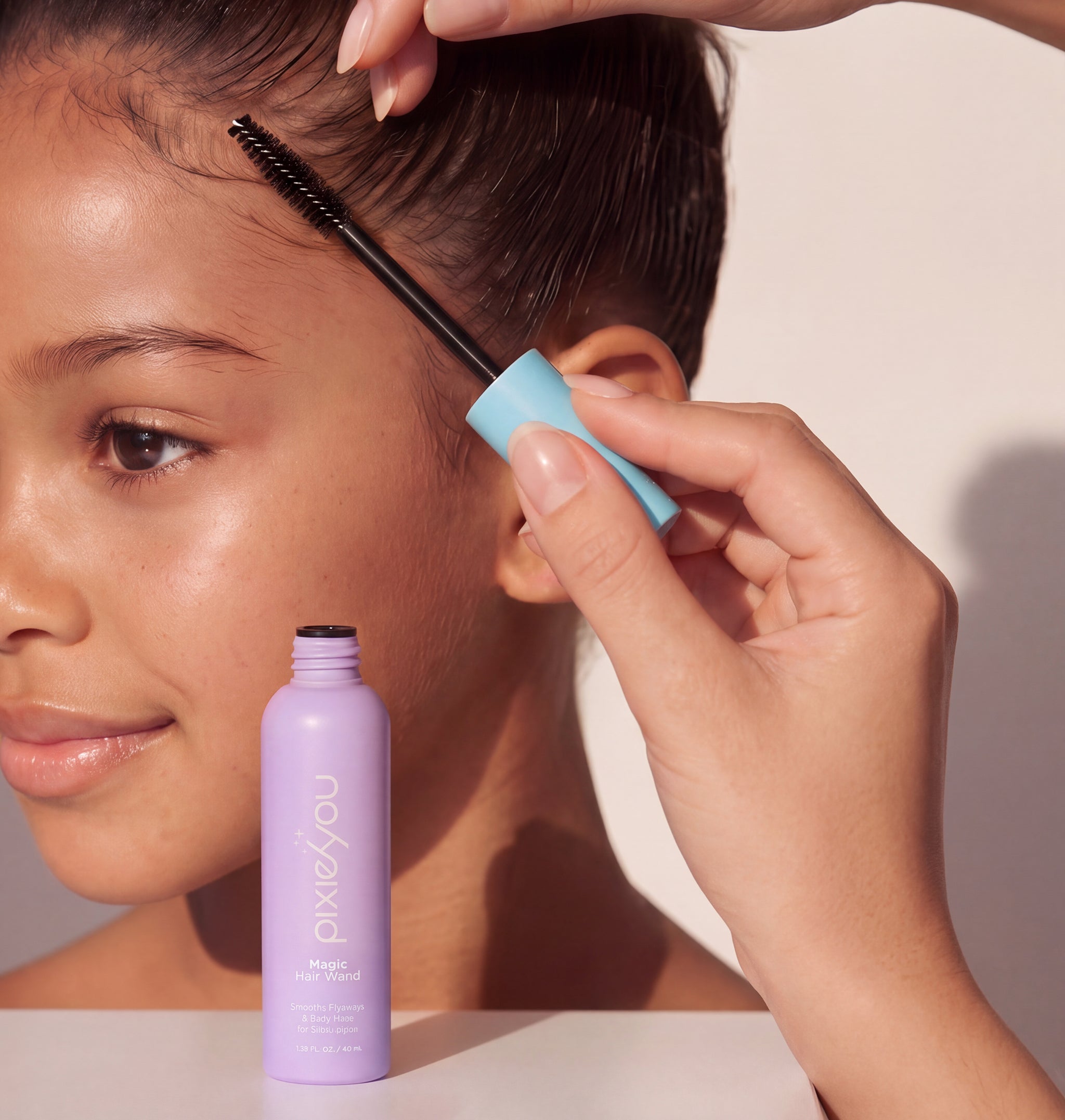 PixieYou Magic Wand in a lavender bottle, with a hand applying product to hair using a brush, on a model's hairline.