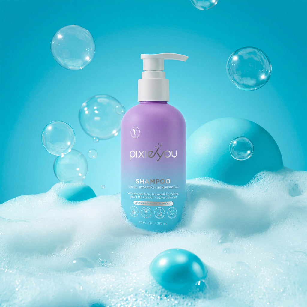 PixieYou Shampoo bottle in purple with a pump, surrounded by bubbles and blue spheres on a bright blue background.