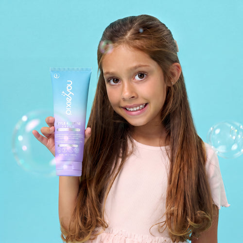 PixieYou Leave-in styling product held by a smiling girl with long hair, surrounded by bubbles against a blue background.